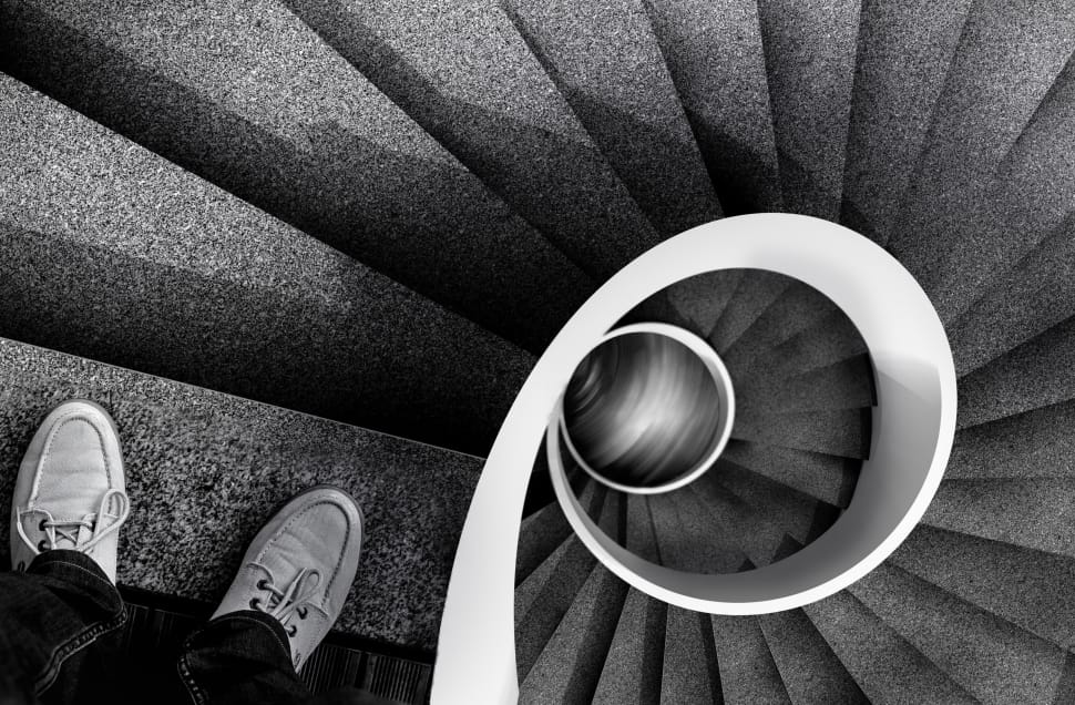 greyscale photo of person on top of spiral stair preview