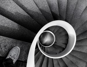 greyscale photo of person on top of spiral stair thumbnail