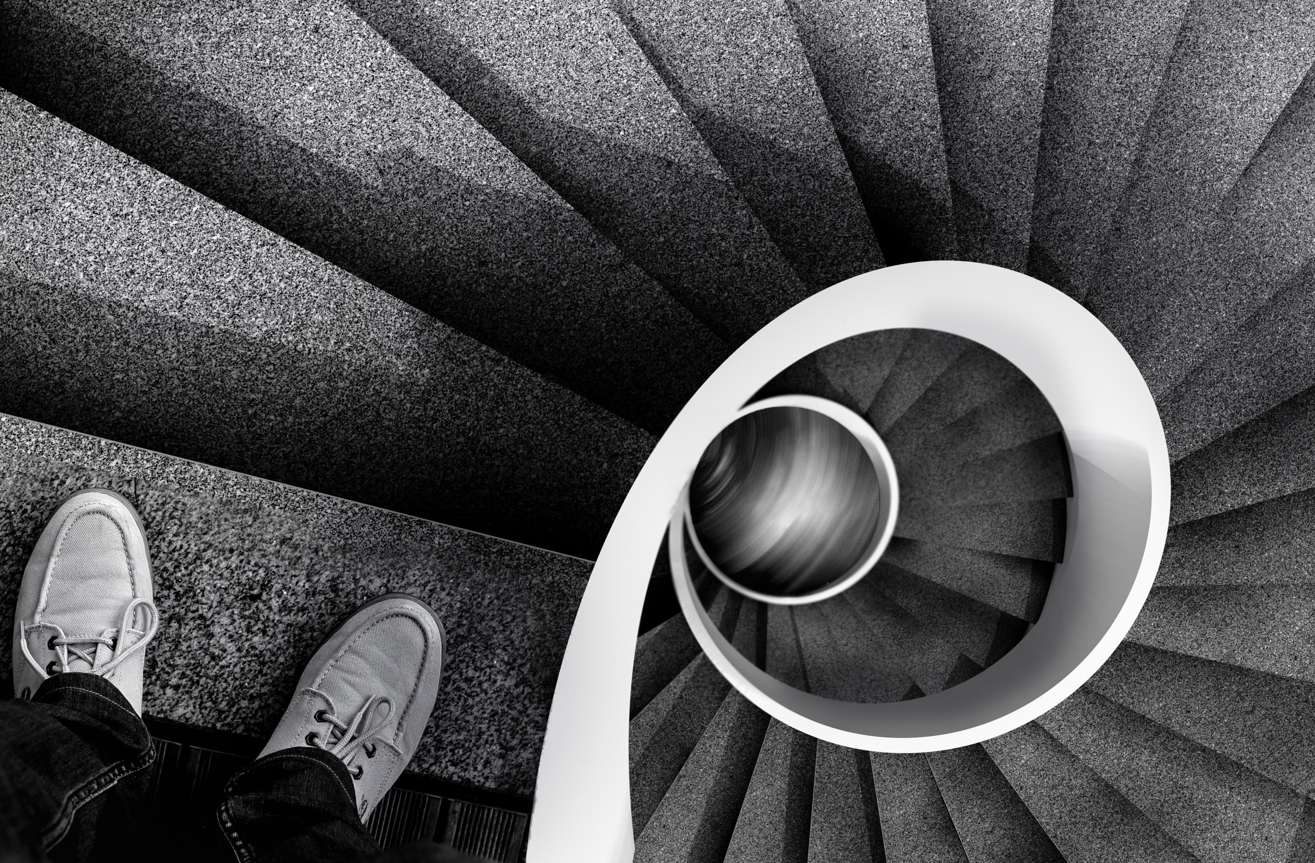greyscale photo of person on top of spiral stair