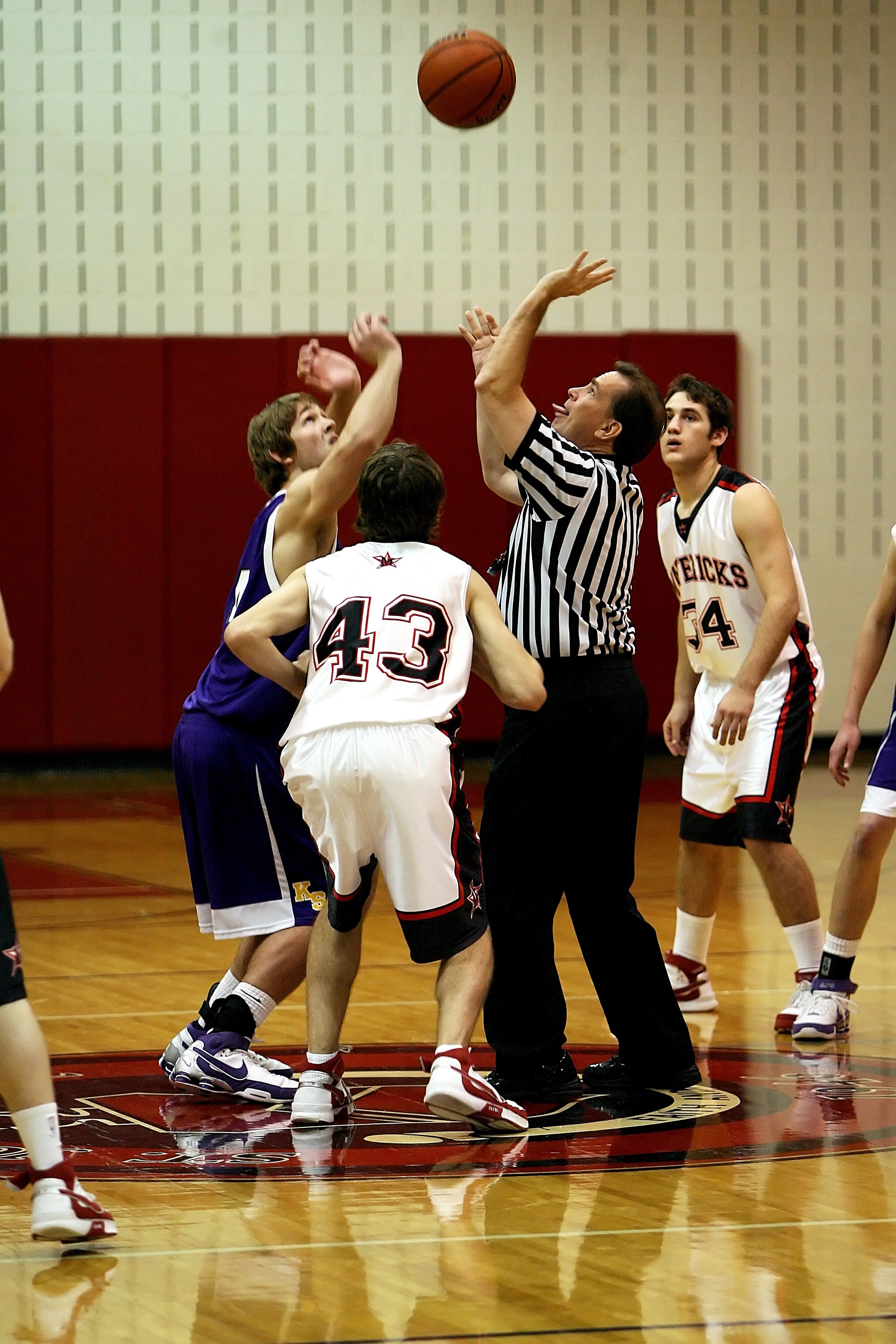 referee tossing the ball upward jumpball basketball game