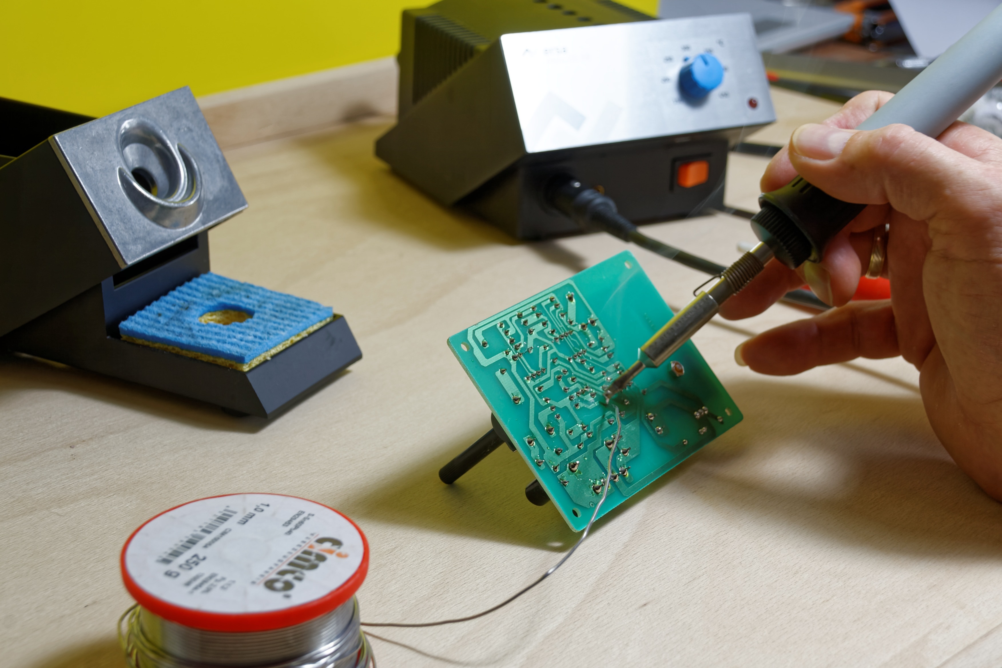 person soldering green circuit board