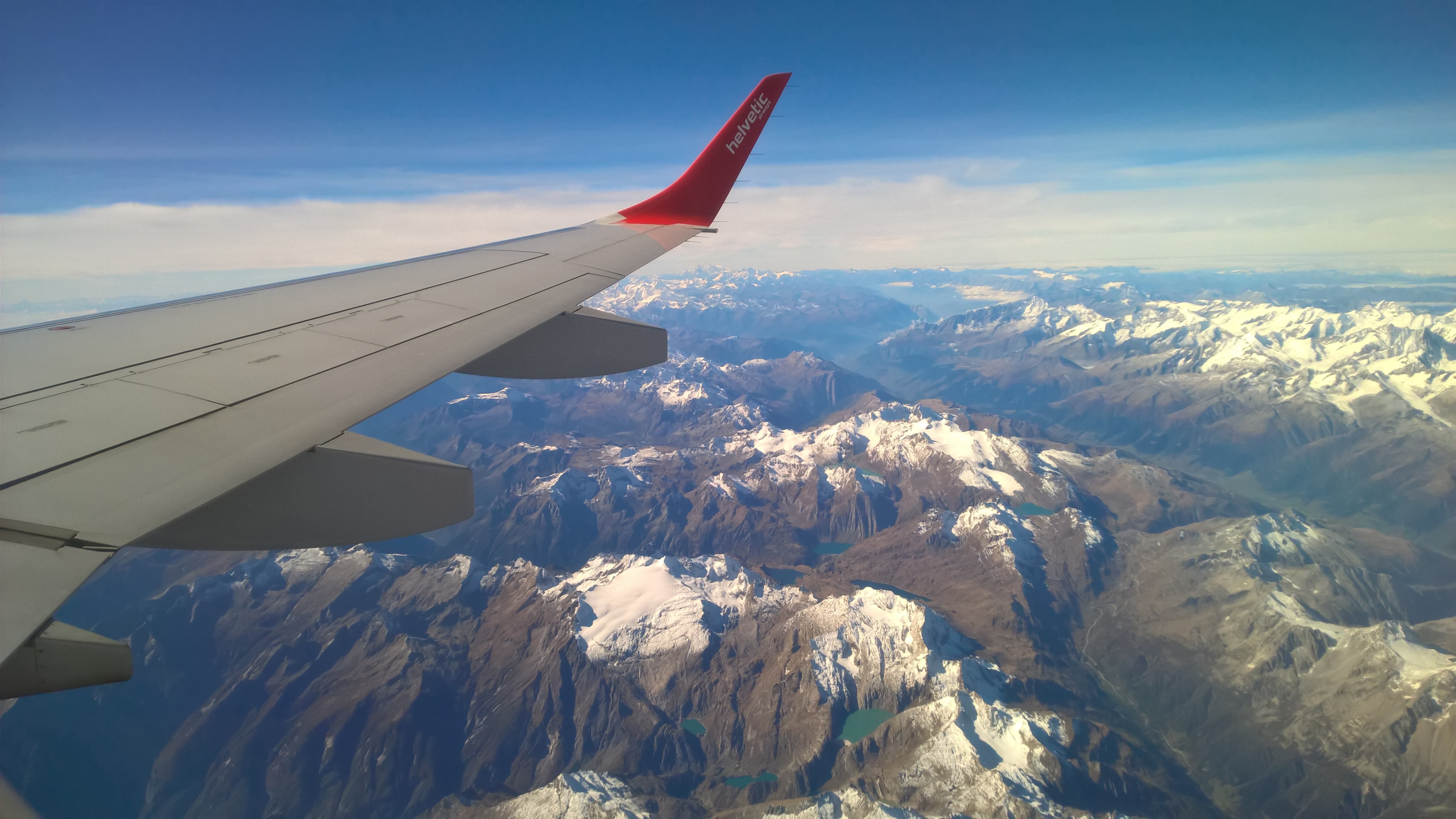 red and gray airplane wings with aerial view photo of snowy mountains