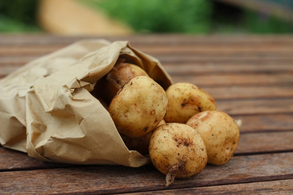 potatoes on brown paper bag above woode platform preview
