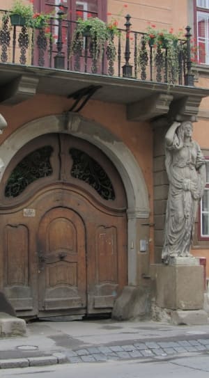 brown wooden arc door with gray concrete female statues thumbnail