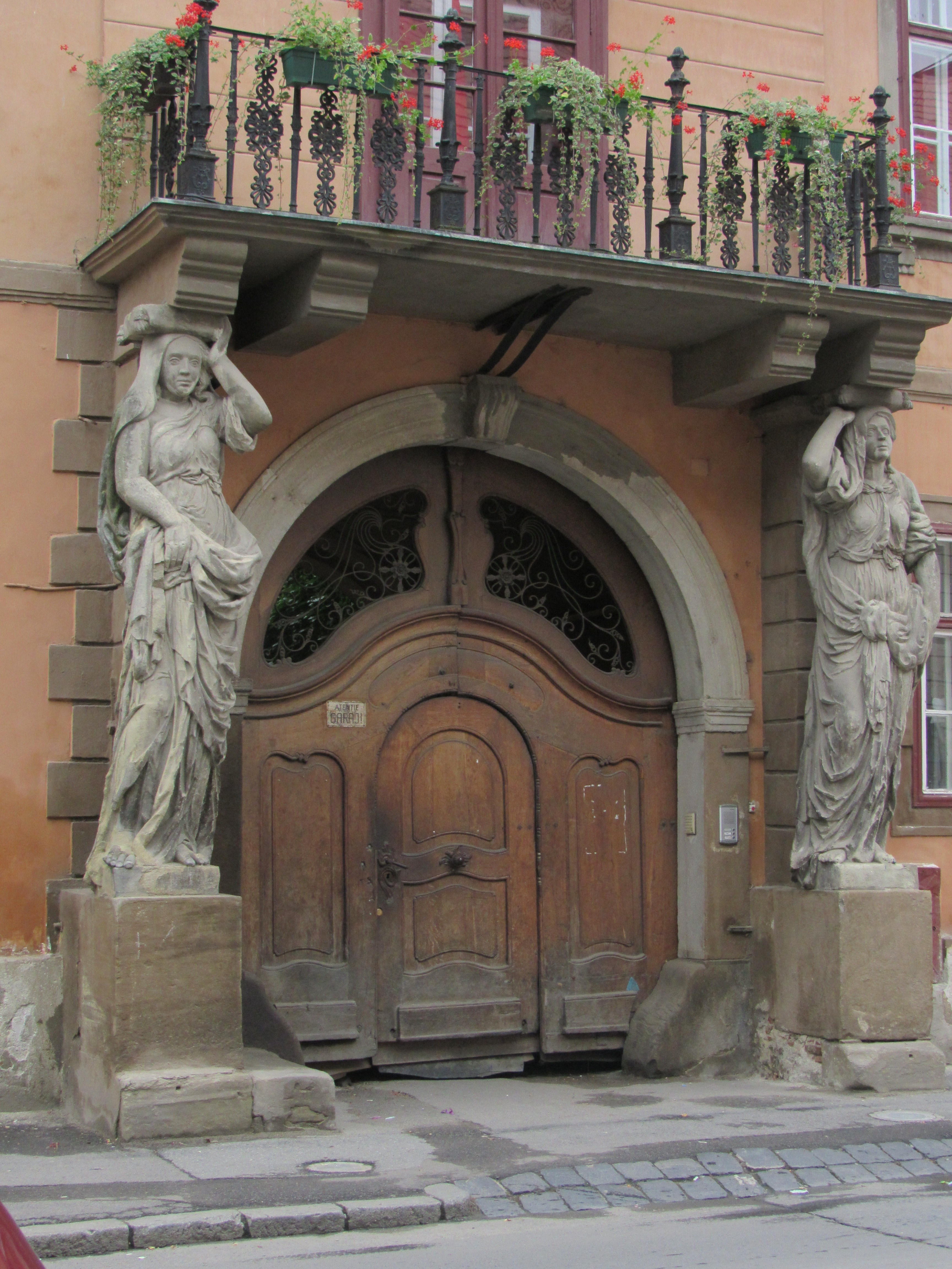 brown wooden arc door with gray concrete female statues