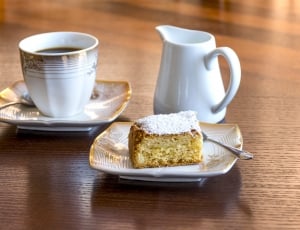 cake on white and brown ceramic saucer beside white ceramic tea cup with saucer thumbnail