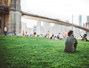 man in gray t-shirt sitting on green grass during daytime thumbnail