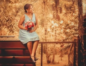 woman wearing in blue dress holding flower during noontime thumbnail