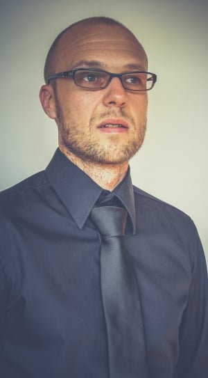 man in black suit and black framed eyeglasses thumbnail