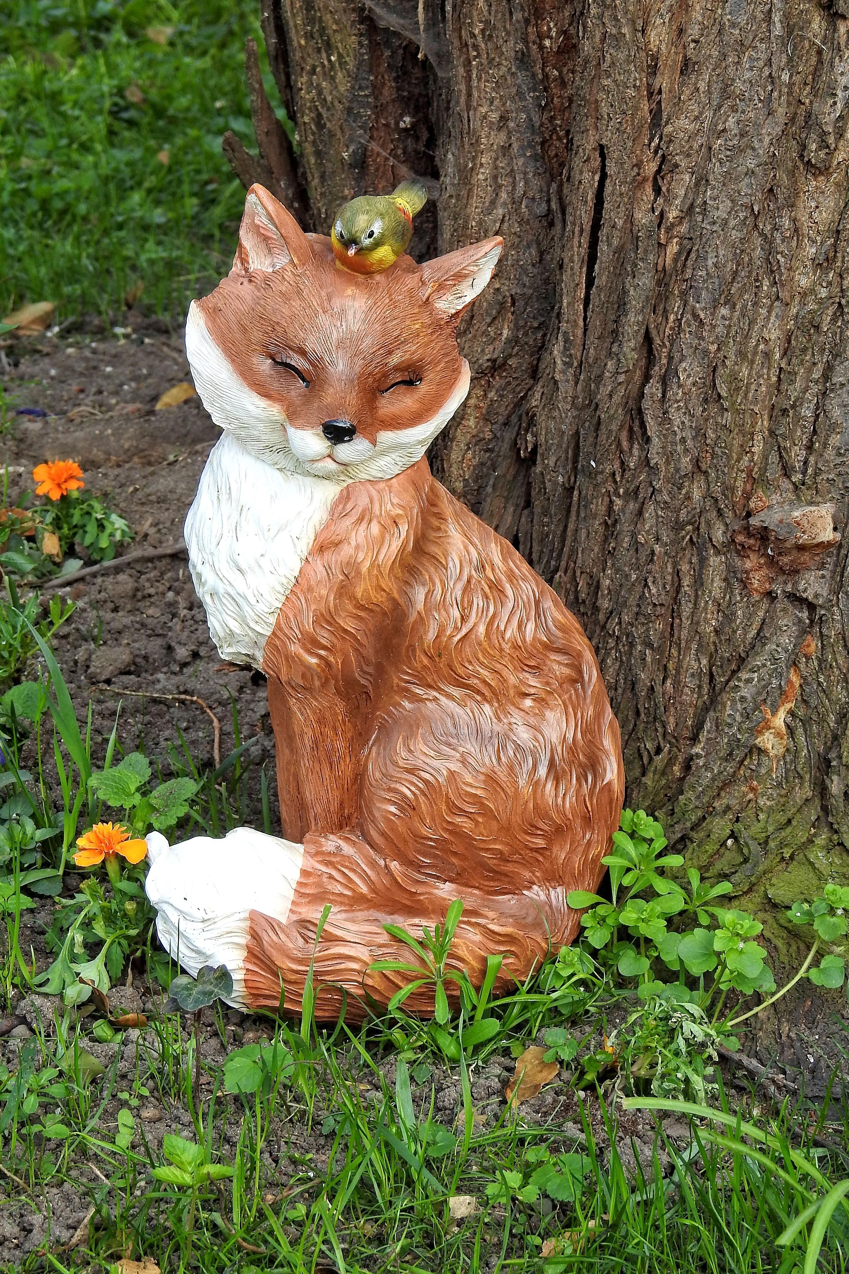 green and yellow bird on head of brown and white fox figurine
