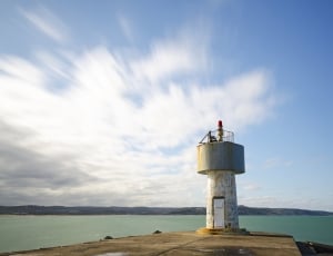 white lighthouse near body of water thumbnail