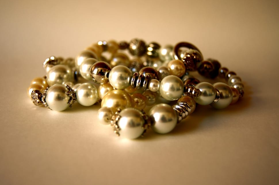 gold and silver pearl bracelets on beige surface preview