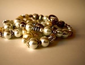 gold and silver pearl bracelets on beige surface thumbnail