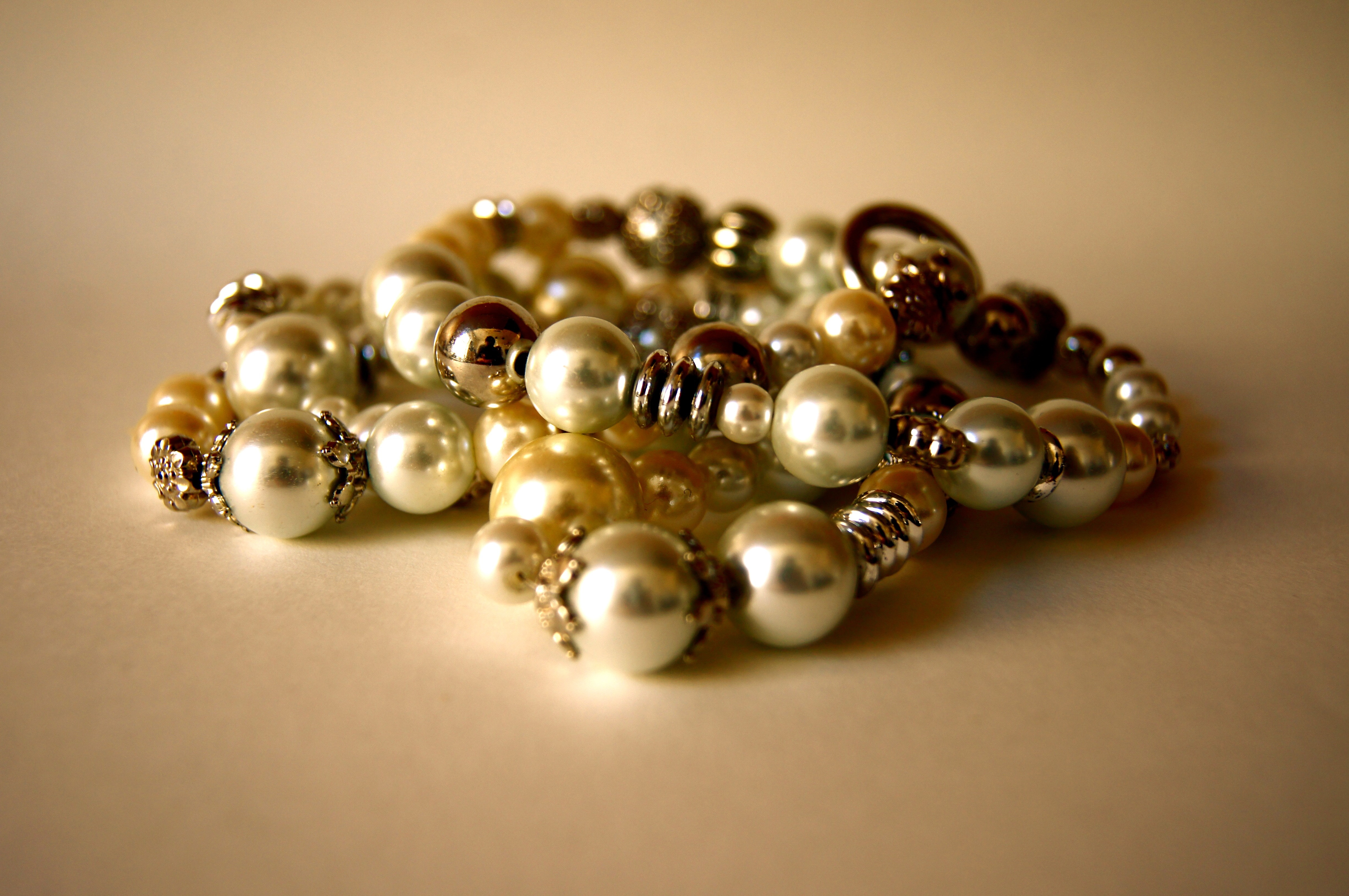 gold and silver pearl bracelets on beige surface
