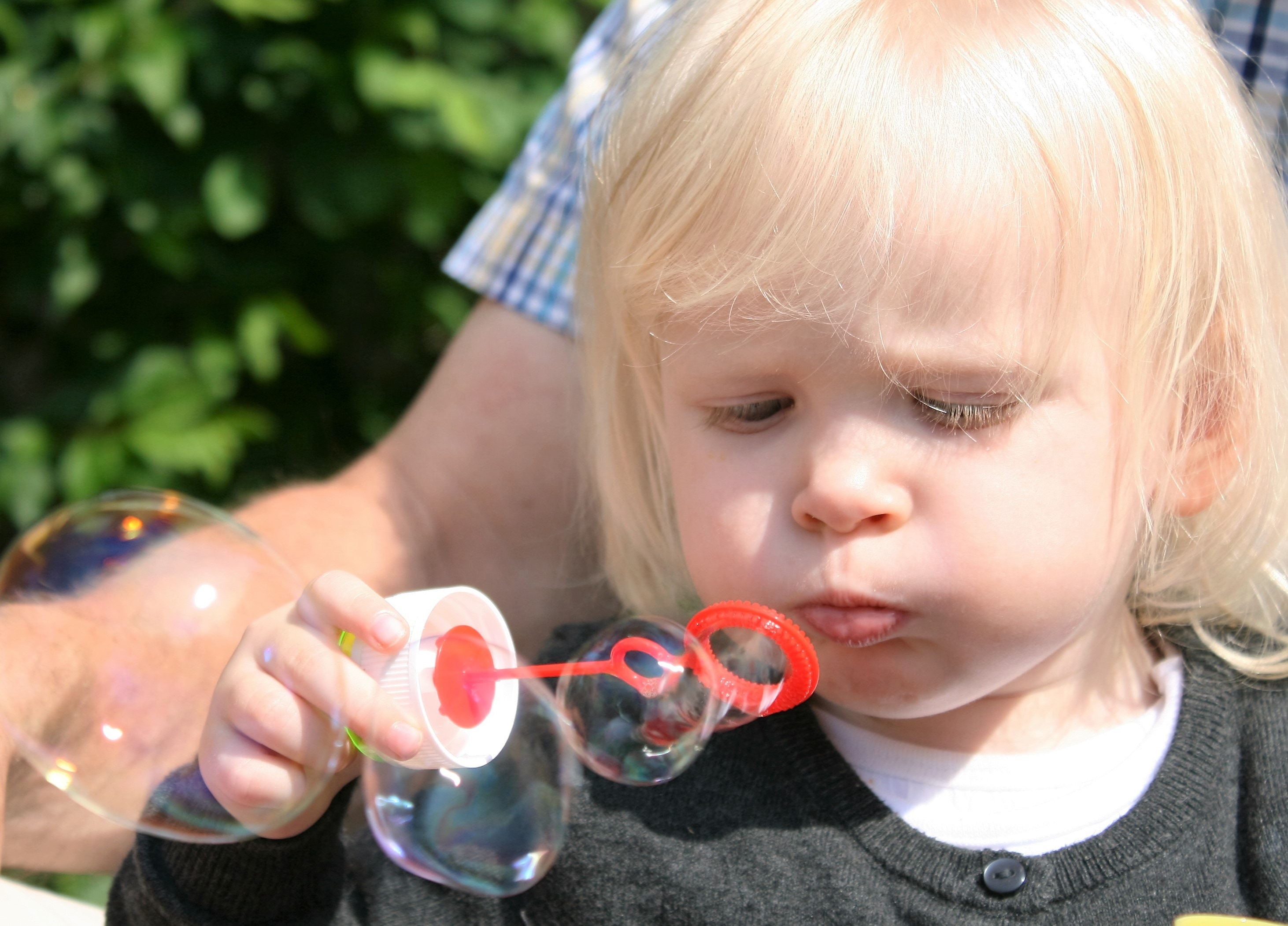 photo of girl holding red blow bubble toy