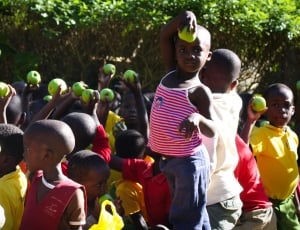 cluster of children holding green round fruit thumbnail
