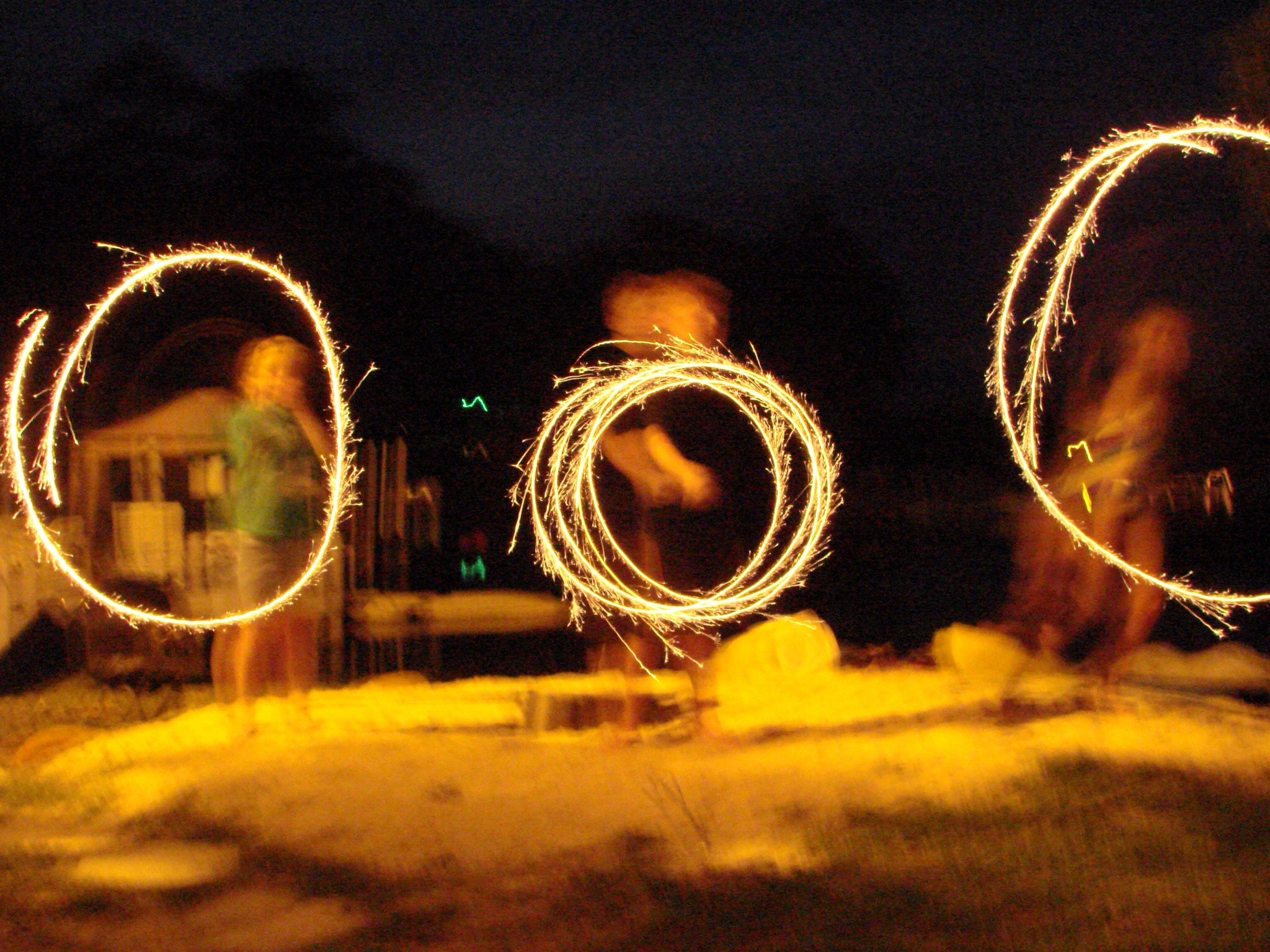 three persons making circular shape with fireworks