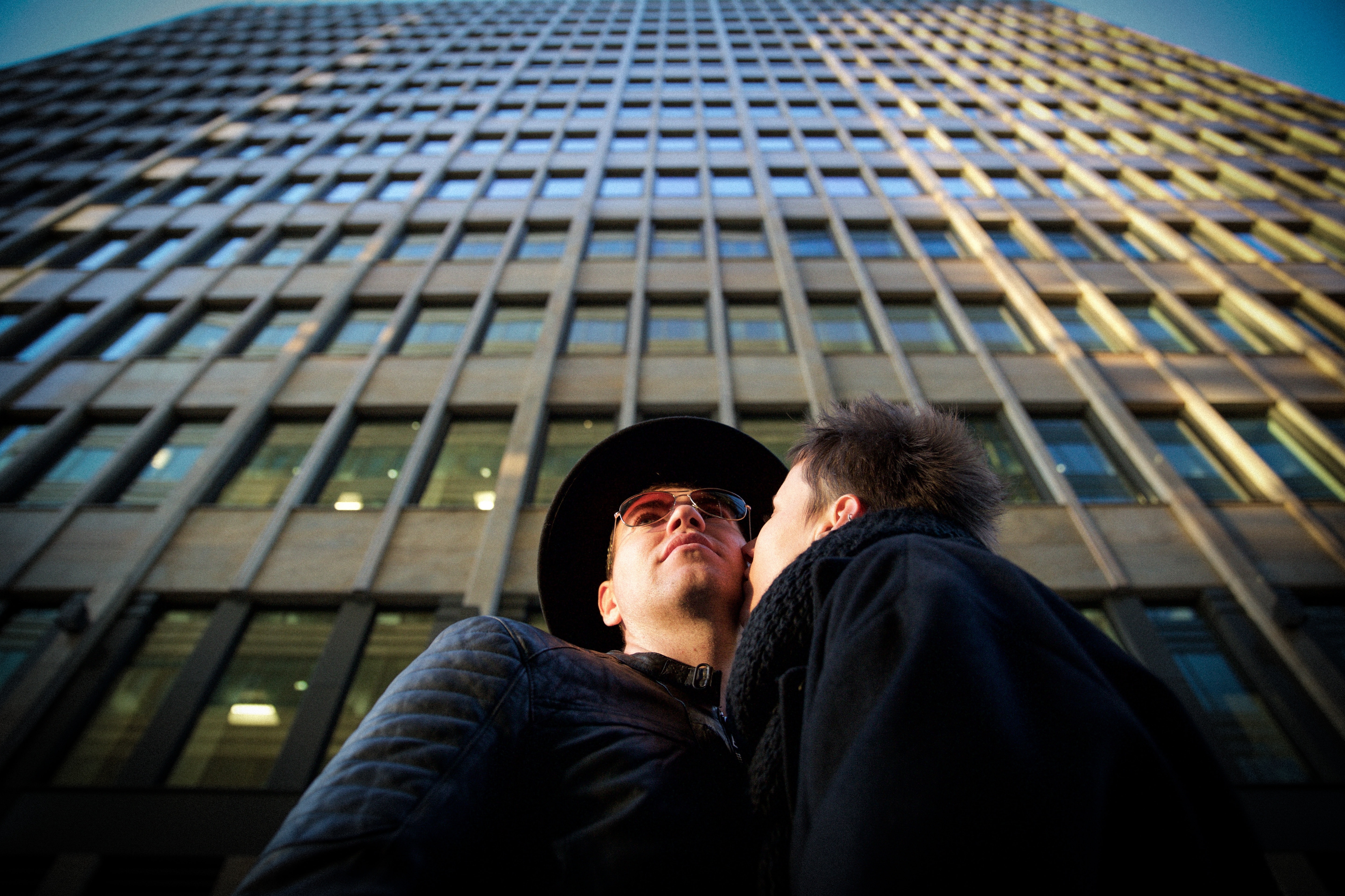 couple kissing near skyscraper during daytime