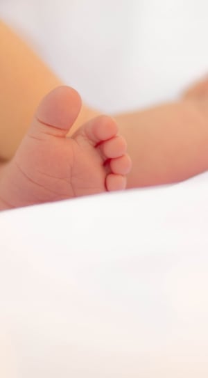 photo showing baby's feet on white textile thumbnail