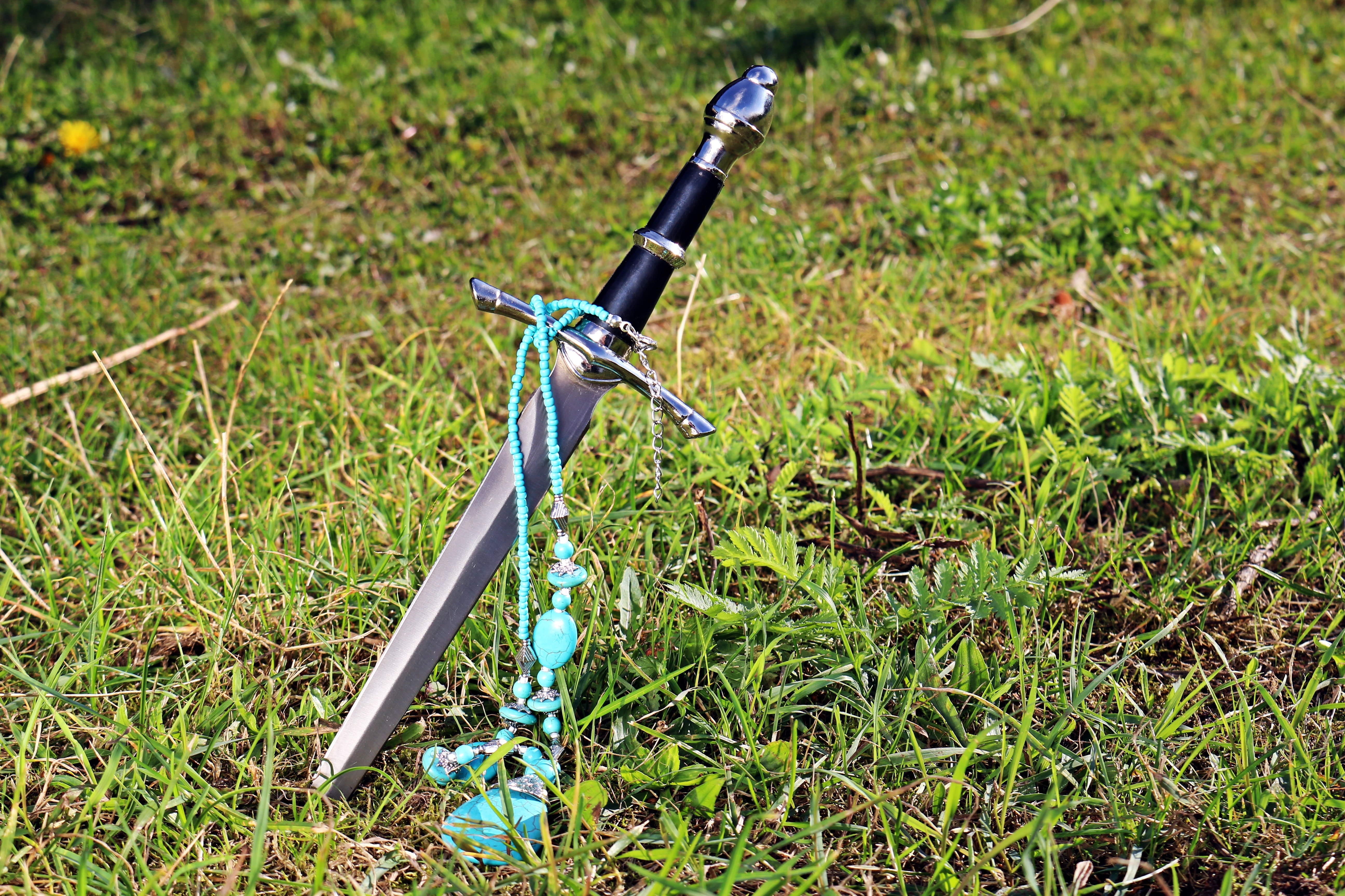 teal beaded necklace and black handled sword
