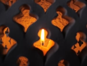 lighted candle inside gray metal grills thumbnail