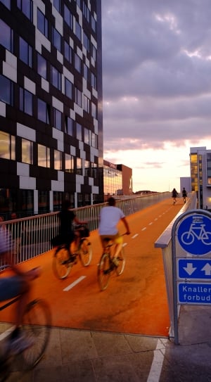 people riding bicycles on orange road thumbnail