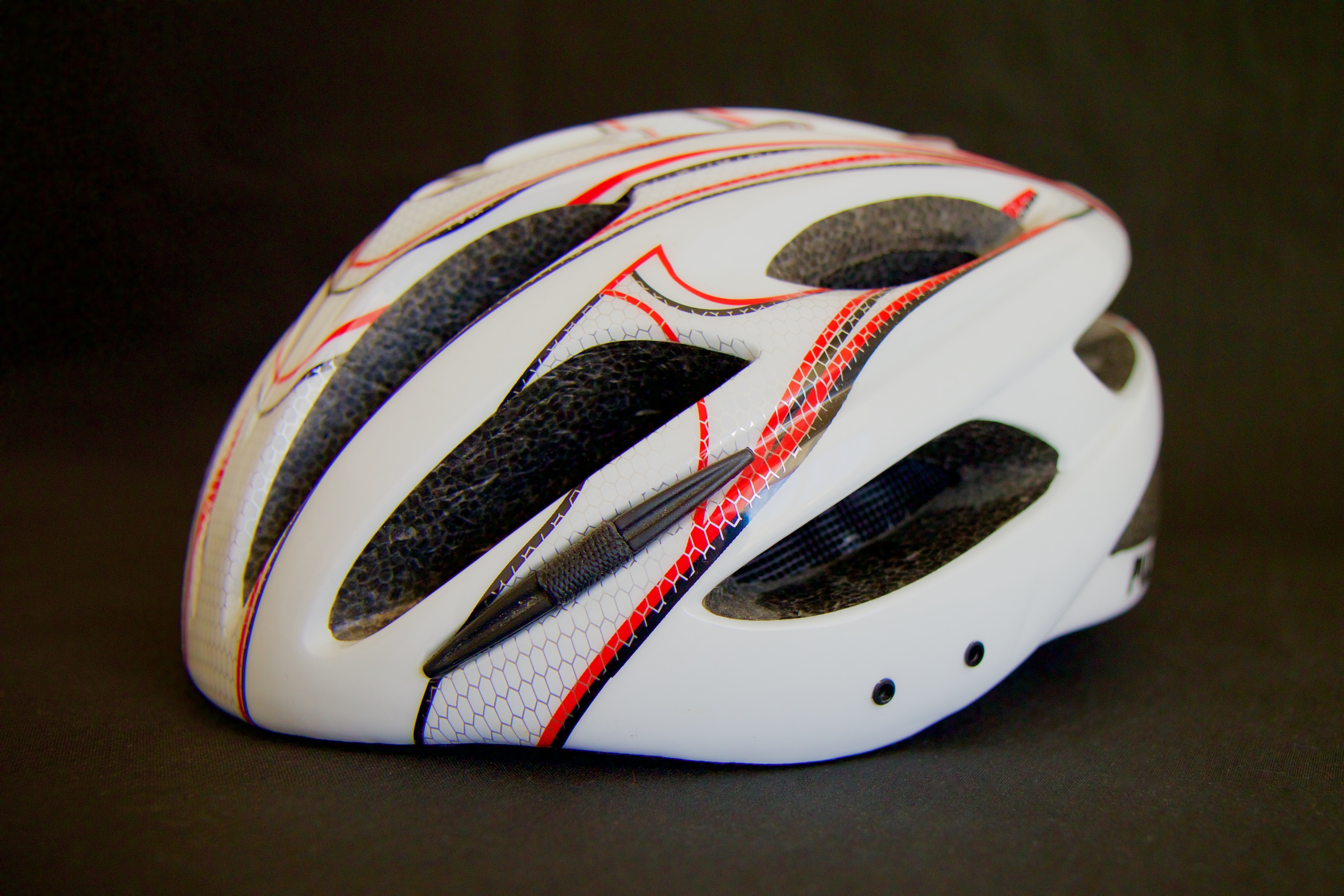white and red bicycle helmet on a black surface