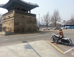 man in brown jacket and black pants outfit riding in cruiser motorcycle thumbnail