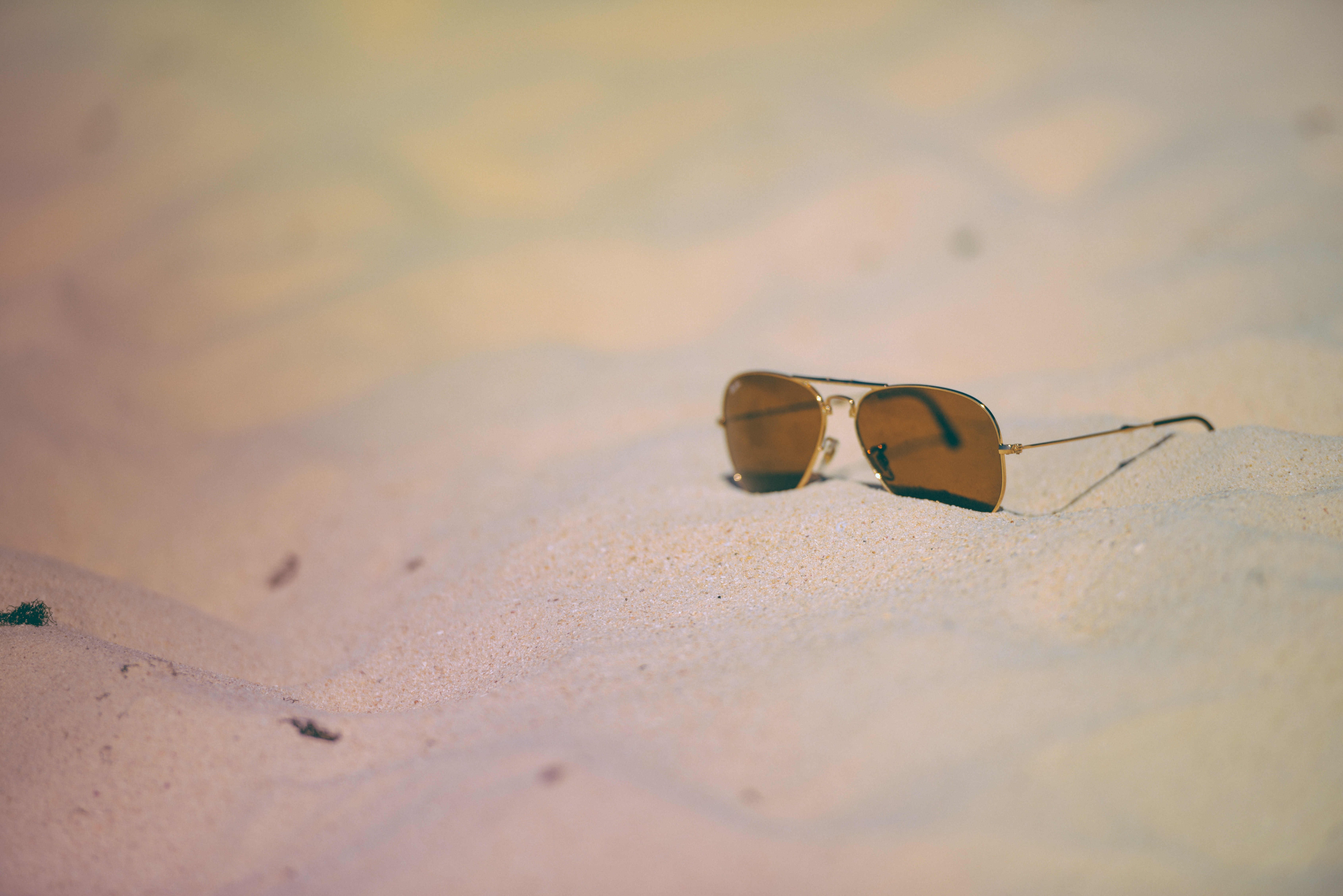 brown aviator sunglasses on white sand