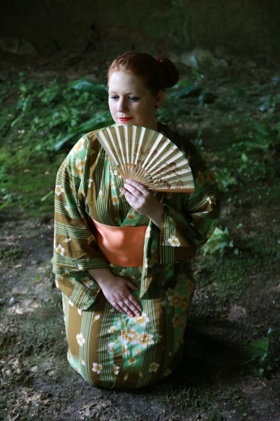 woman wearing green and brown floral kimono and holding folding fan preview