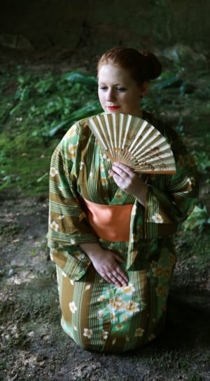 woman wearing green and brown floral kimono and holding folding fan thumbnail