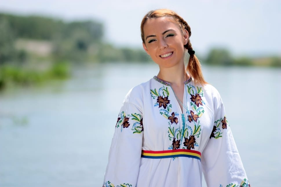 woman wearing white blue green and red printed long sleeve dress near body of water during daytime preview