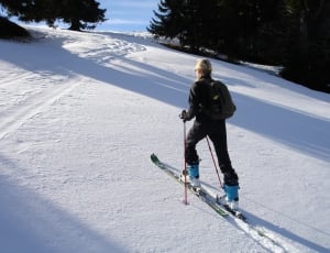 photography of person climbing snow mountain using snow skis thumbnail