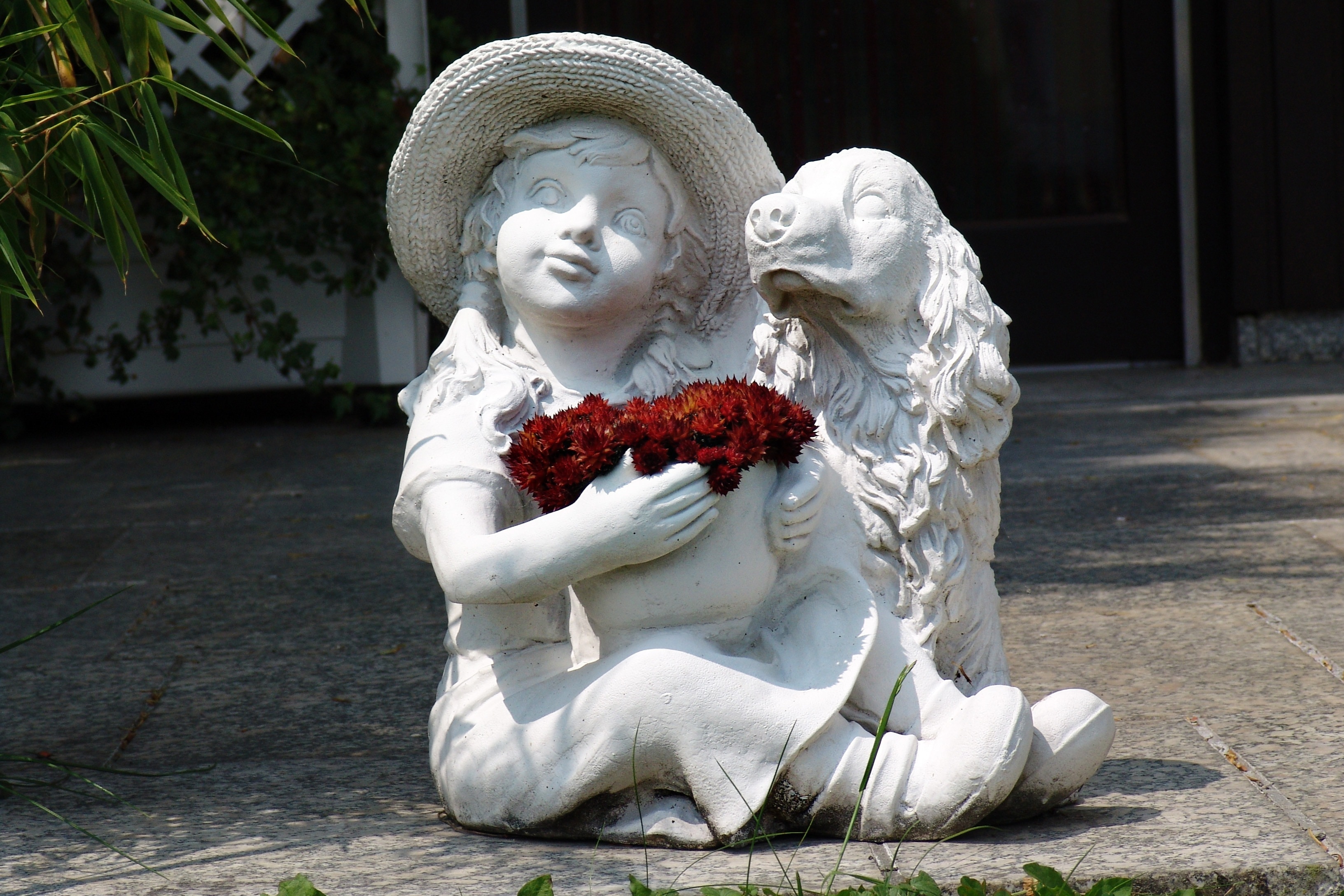 girl holding red flower bouquet beside the Cocker Spaniel statuette