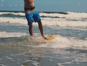 beige surfboard and cyan and gray windshorts thumbnail