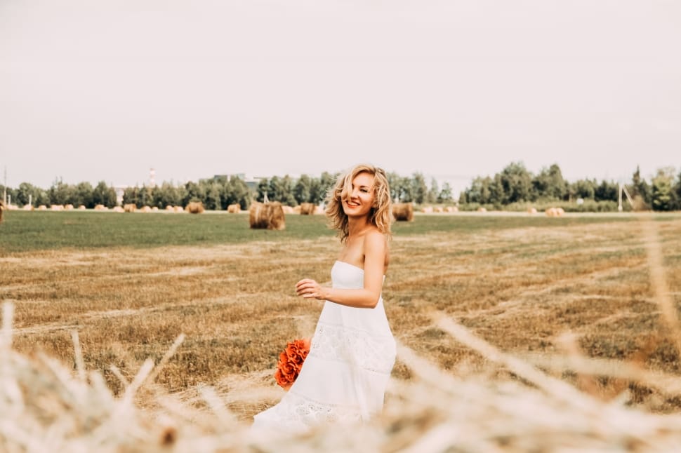 woman in white floral dress standing on grass field during daytime preview