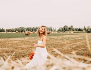 woman in white floral dress standing on grass field during daytime thumbnail