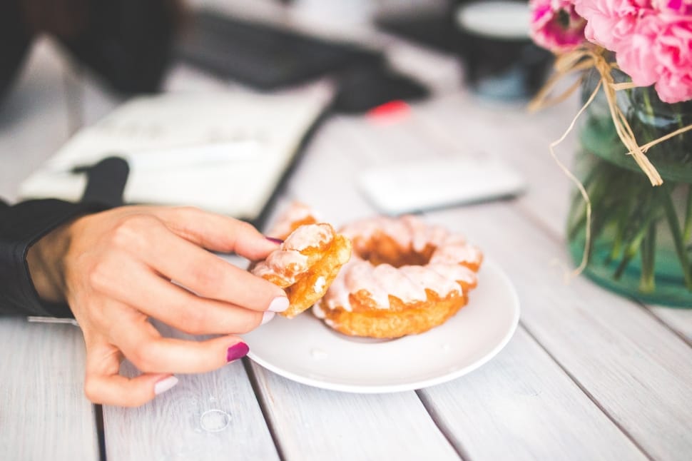 person holding doughnut on white ceramic plate preview