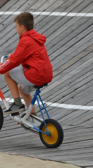 boy's red hooded jacket riding on bicycle at daytime thumbnail