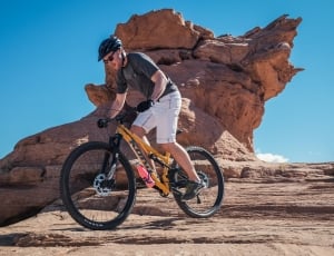 man riding yellow full suspension bike on brown rock mountain thumbnail