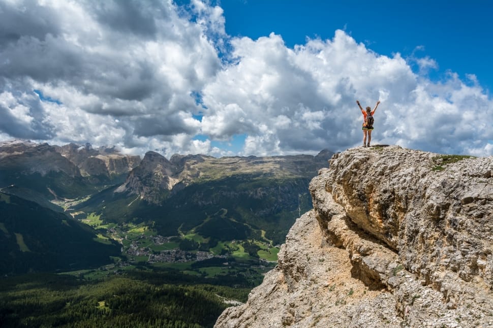 person raising hand standing on top of mountain cliff preview