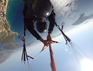 person flying with parachute facing body of water thumbnail