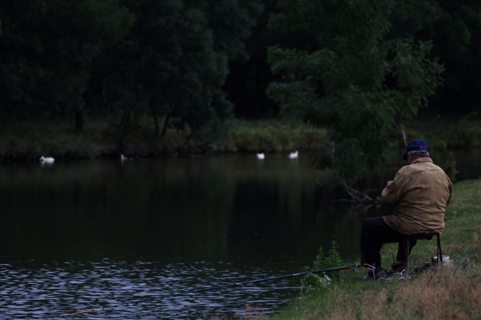man in brown jacket fishing on lake during daytime preview