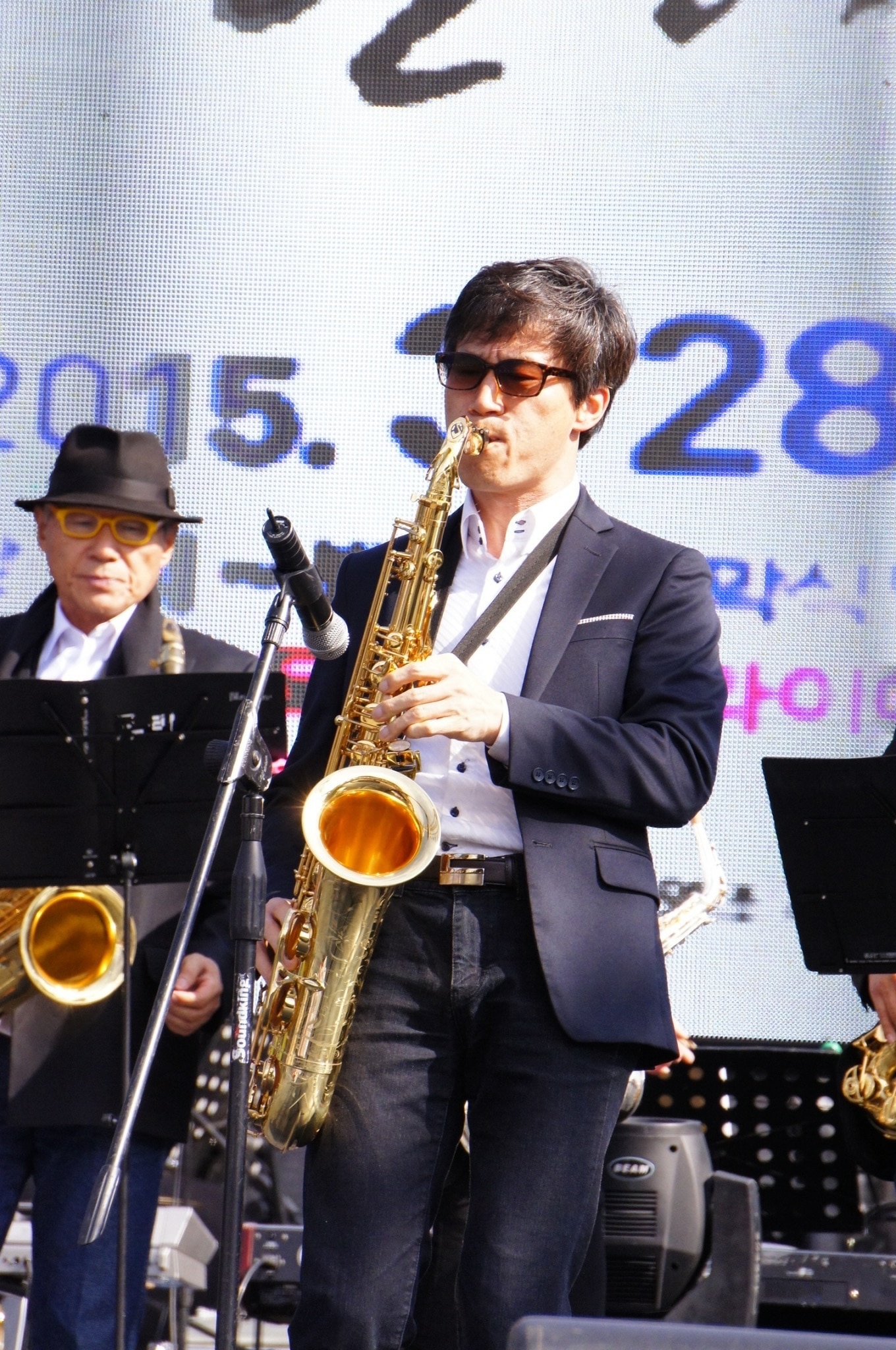 man playing brass saxophone on stage