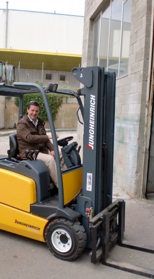 man smiling sitting on black and yellow Jungherich fork lift thumbnail