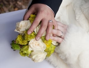 bride and groom's hands holding bouquet of white and green flowers thumbnail