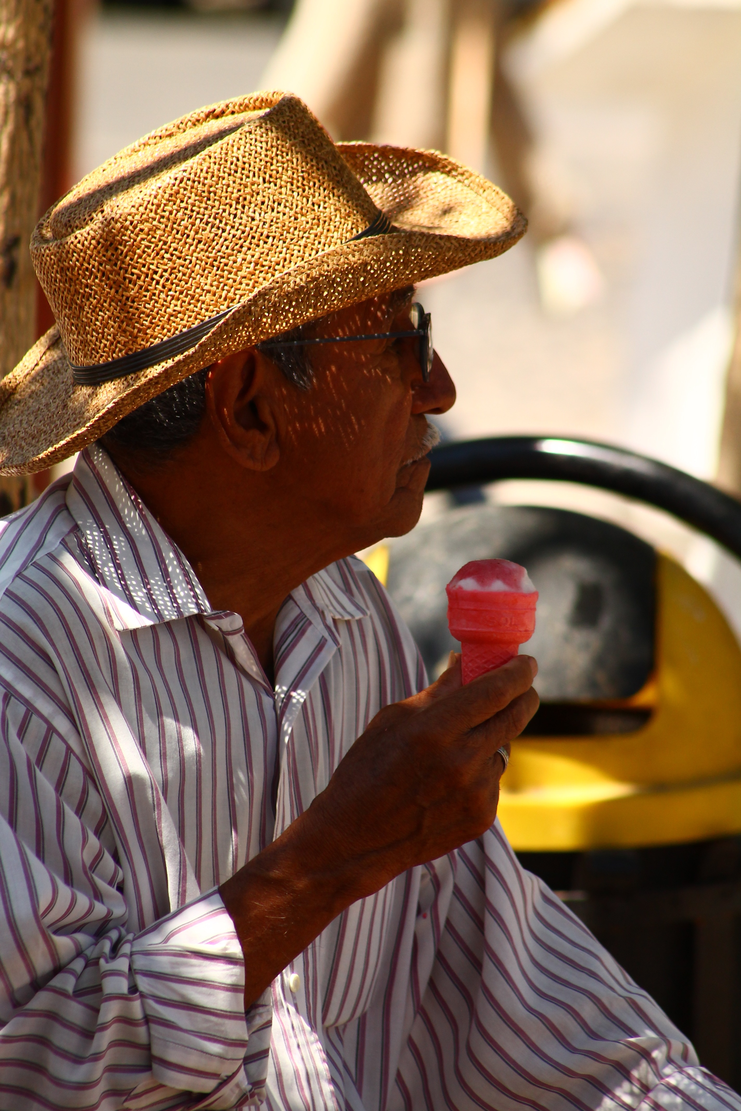 man in brown and white striped dress shirt wearing fedora hat holding ice cream