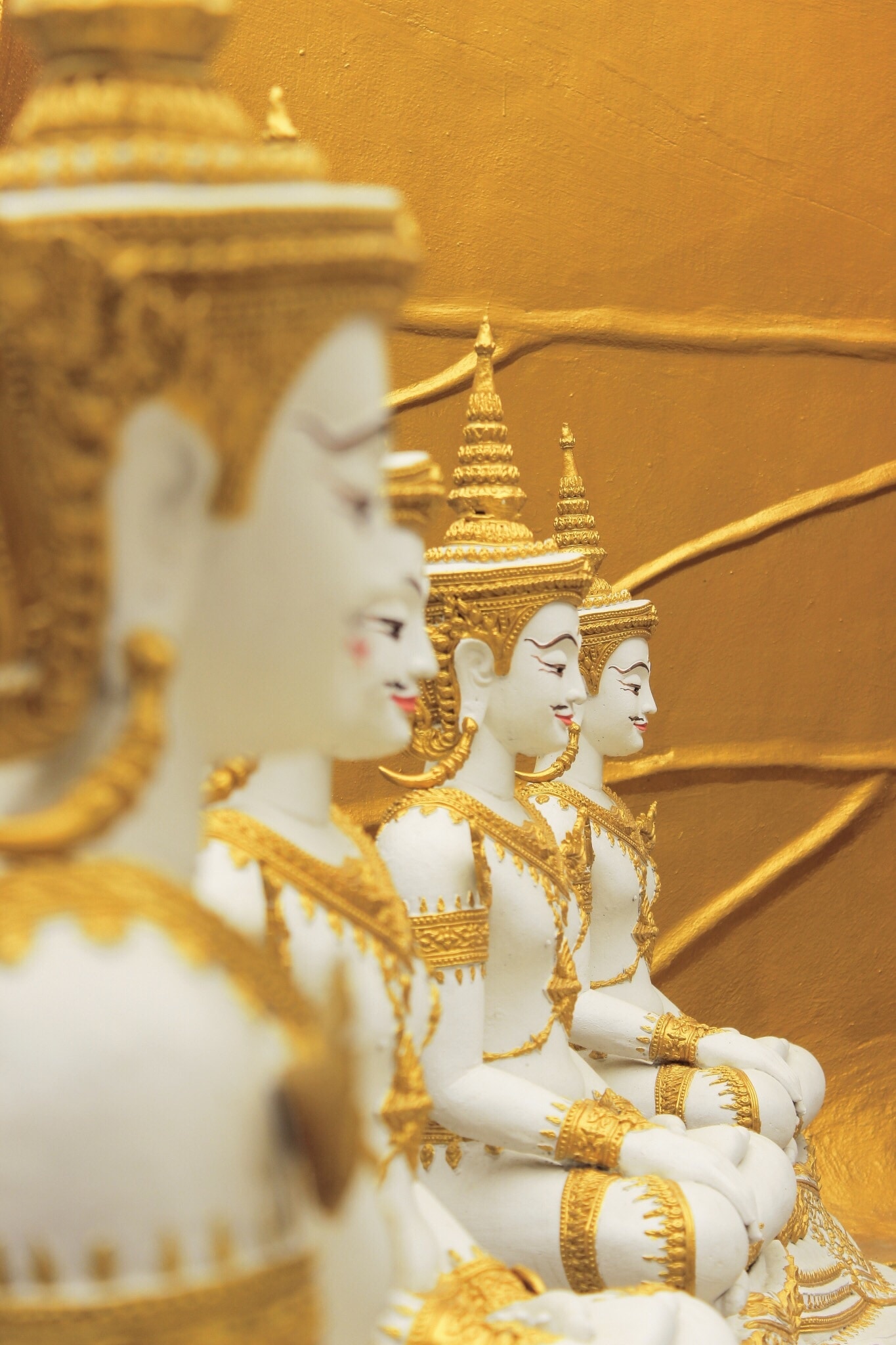 four white and gold ceramic buddha figurines