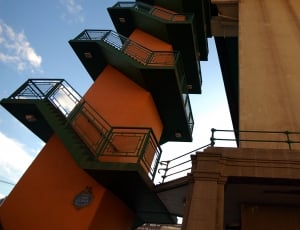 orange and green mid rise building with 5 tier stairway during daytime thumbnail