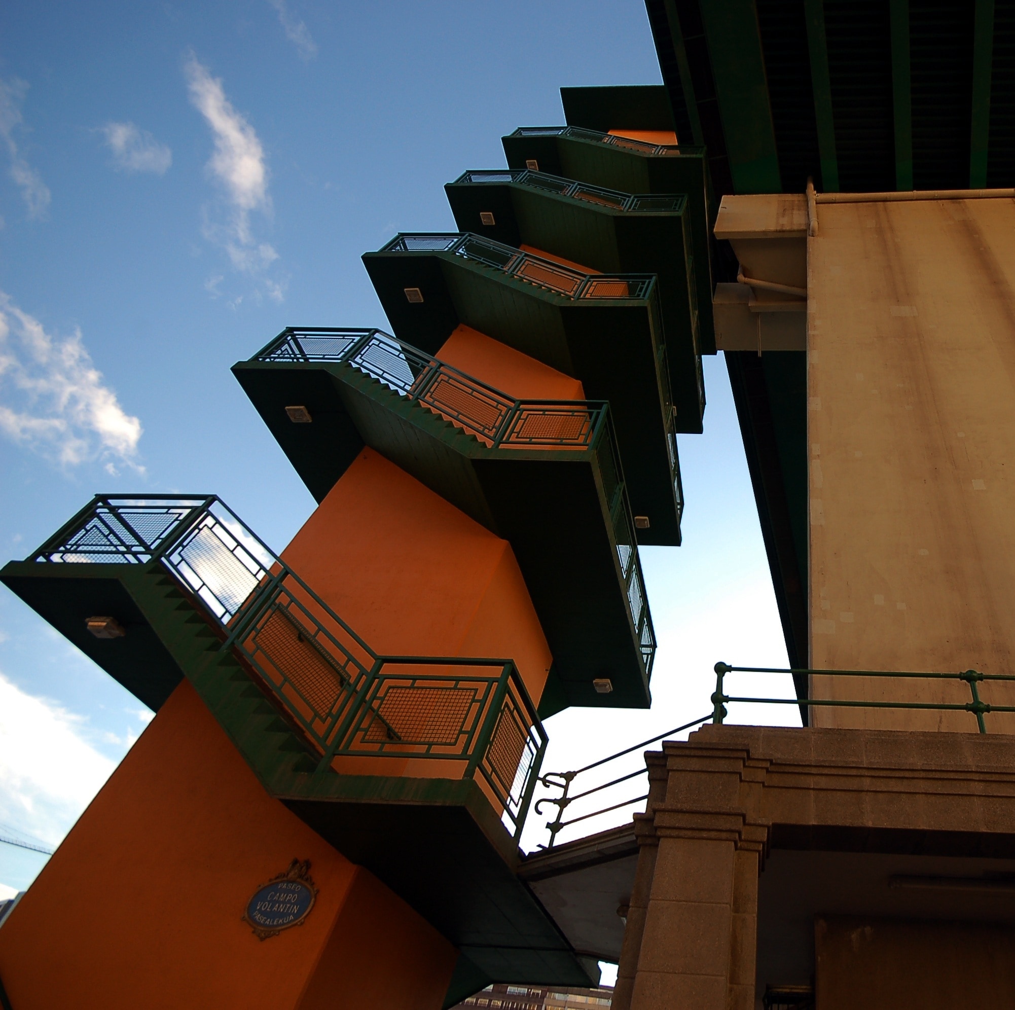 orange and green mid rise building with 5 tier stairway during daytime